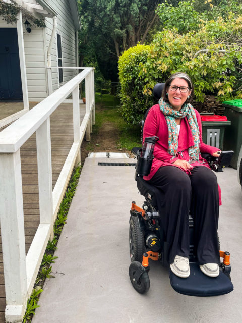 A young woman in a motorised wheelchair on her driveway