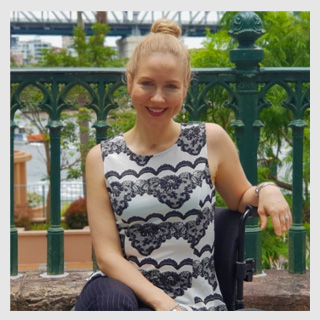 Youngcare ambassador, Lisa Cox, smiling and sitting in wheelchair alongside the Brisbane River